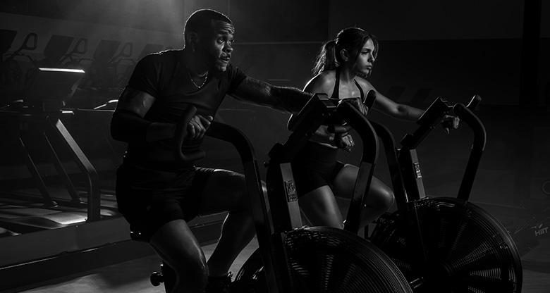gym members next to each other riding assault bikes