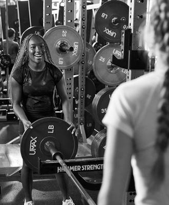 gym members moving weights and smiling