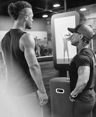 a group photo of several different members of gym staff standing and pointing to the body scan machine