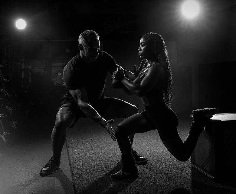 Personal trainer giving guidance to a woman on a rowing machine in a gym